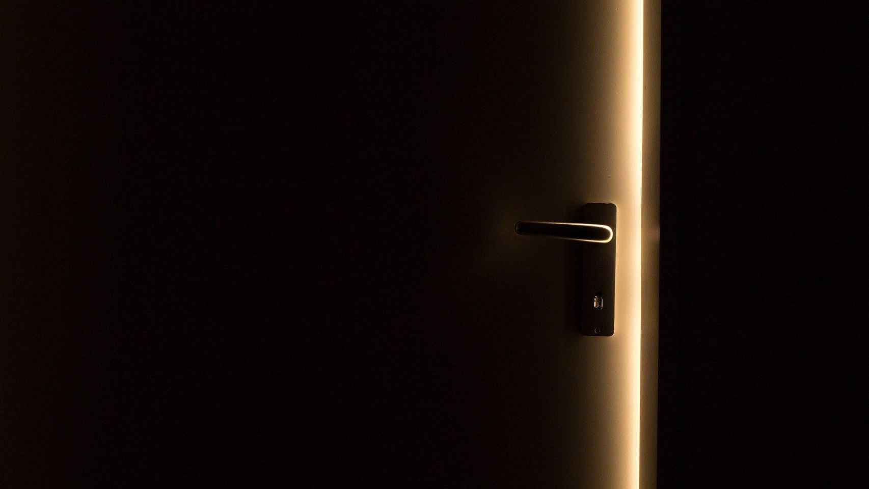 La puerta de una casa, medio abierta entre la oscuridad / CG