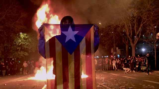 Un manifestante blande una bandera estelada frente a contenedores en llamas en los alrededores del Camp Nou / EB
