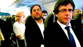 El presidente Carles Puigdemont (d), el vicepresidente Oriol Junqueras (c) y el consejero de Exteriores Raül Romeva (i), en el avión que les llevó a Bruselas para pronunciar una conferencia sobre el referendum independentista / JORDI BEDMAR
