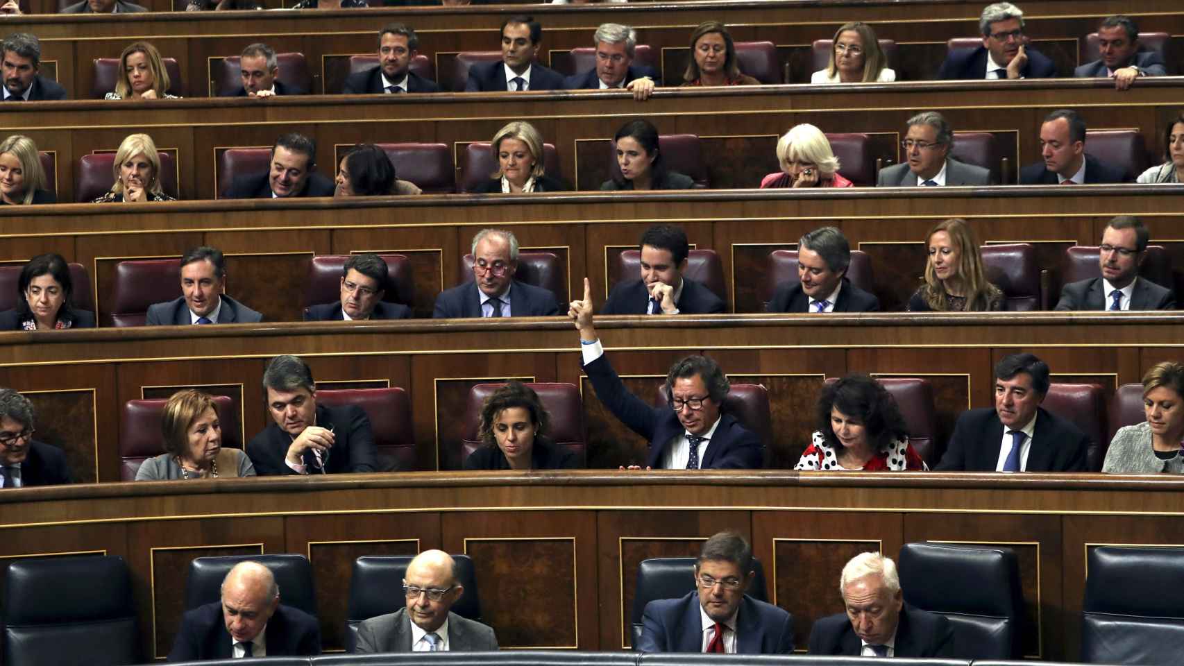 El diputado del PP Carlos Floriano (4d, segunda fila) marca el sentido del voto a sus compañeros de partido, durante un pleno en el Congreso de los Diputados | EFE