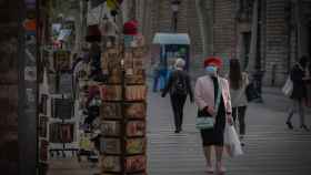 Una mujer frente a una tienda de artículos turísticos en una Barcelona vacía por el Covid / EP