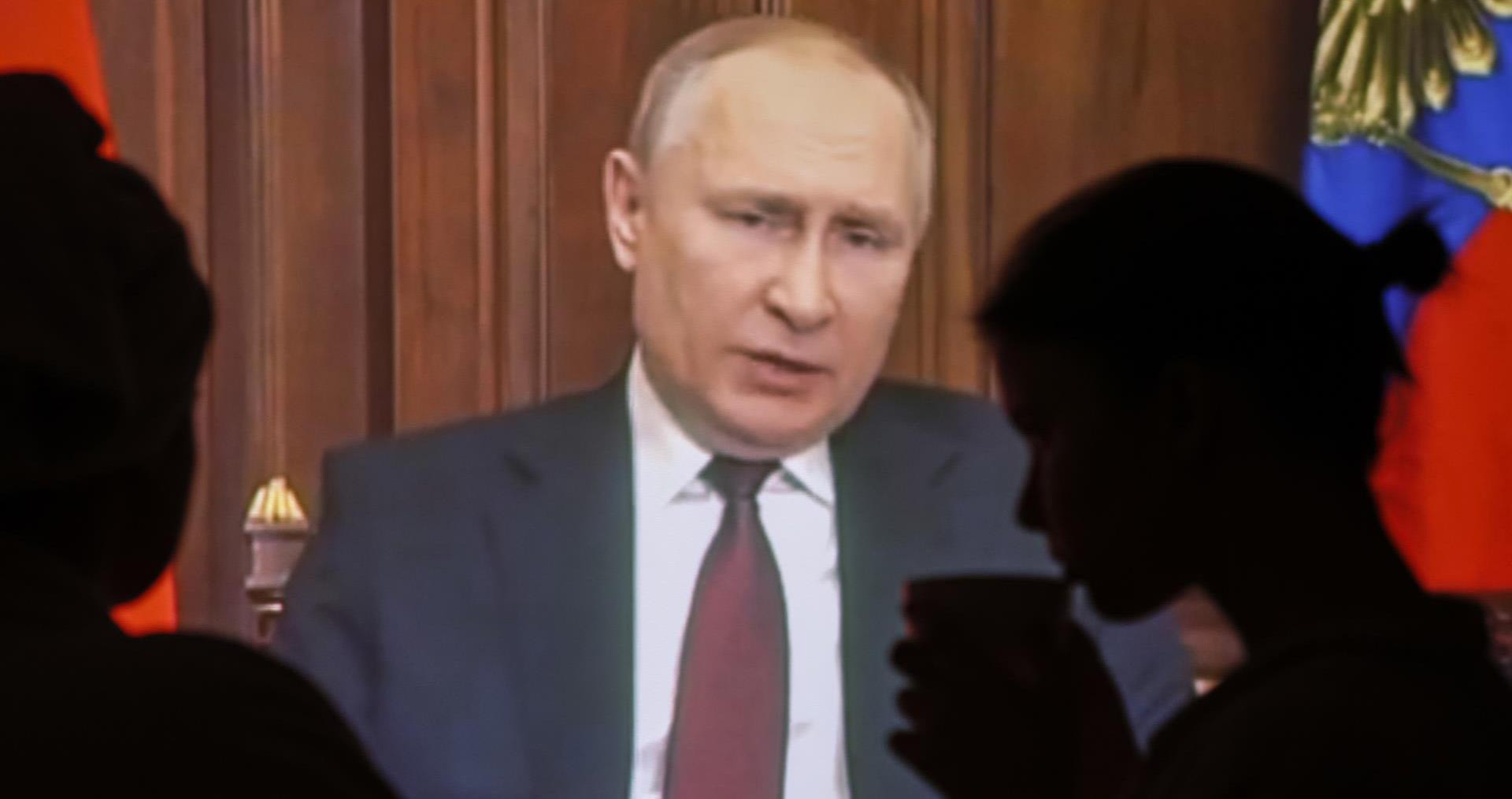 Dos personas observan el discurso televisado del presidente ruso Vladimir Putin en Moscú, Rusia en el que ha anunciado el comienzo de una operación militar en este de Ucrania / EFE