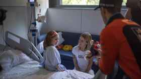 Una niña ingresada recibiendo un regalo de los pilotos de Moto GP en el Hospital Universitari Dexeus / LENA PRIETO