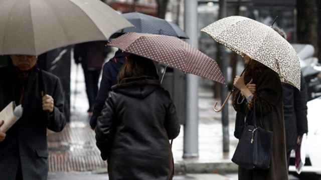 Varias personas caminan por la calle bajo la lluvia / EP