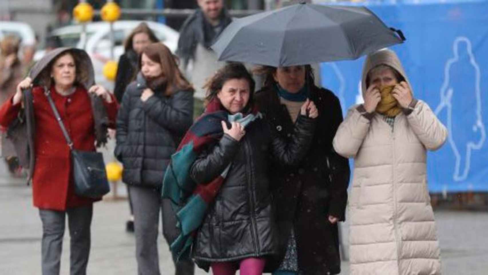 Un grupo de personas se protege del frío y de la lluvia en Madrid / EFE