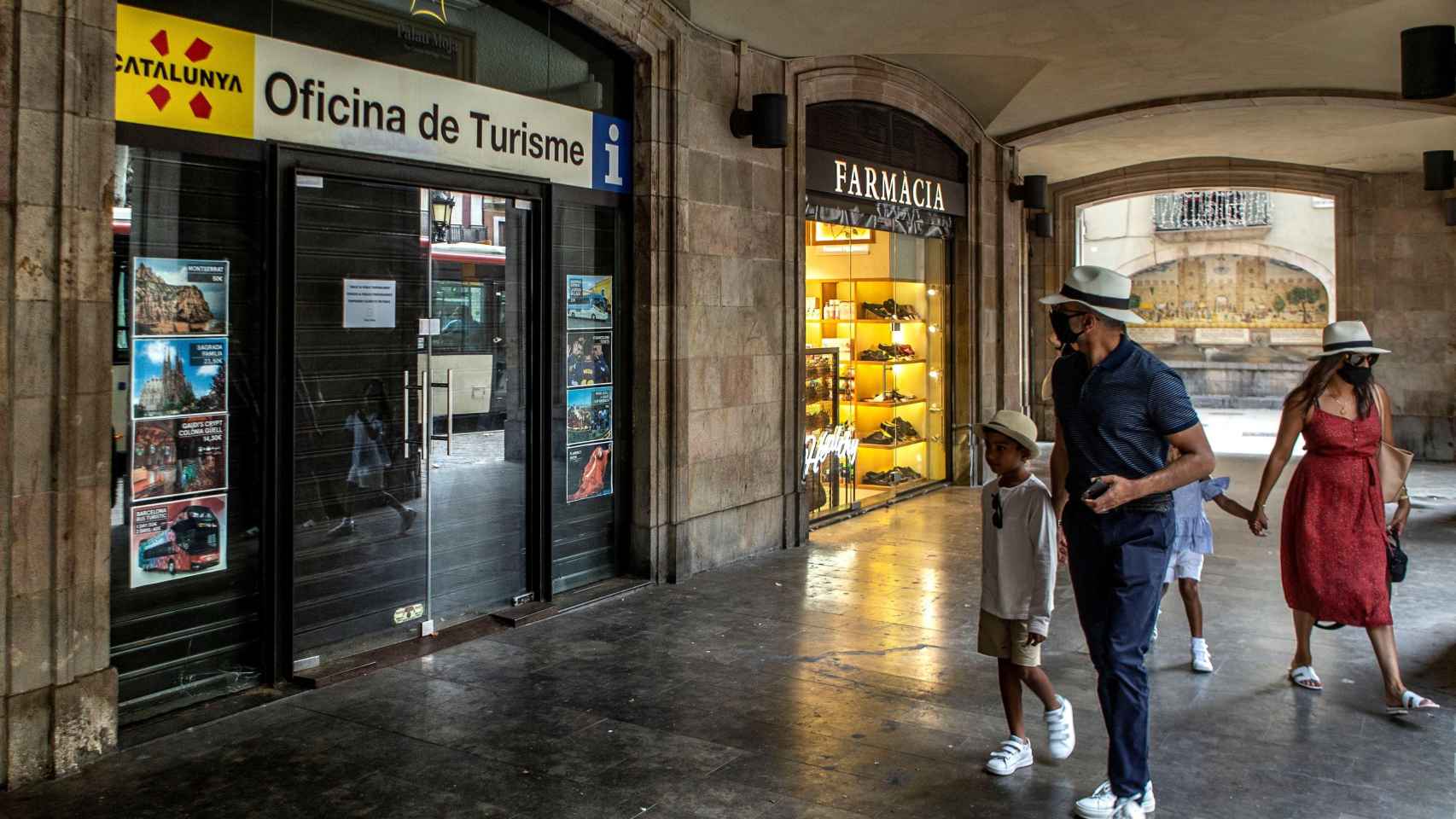 Una familia de visitantes, ante una oficina de turismo de Cataluña cerrada en el centro de Barcelona / EFE