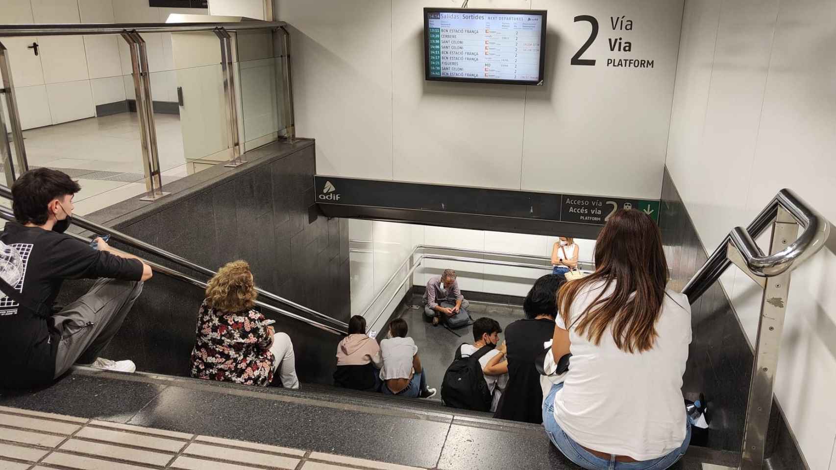 Diferentes personas esperando en la entrada a uno de los andenes de la estación de paseo de Gràcia, a la que prácticamente no se podía acceder, por el colapso de los servicios mínimos y las aglomeraciones a la espera de que llegaran los trenes de Rodalies