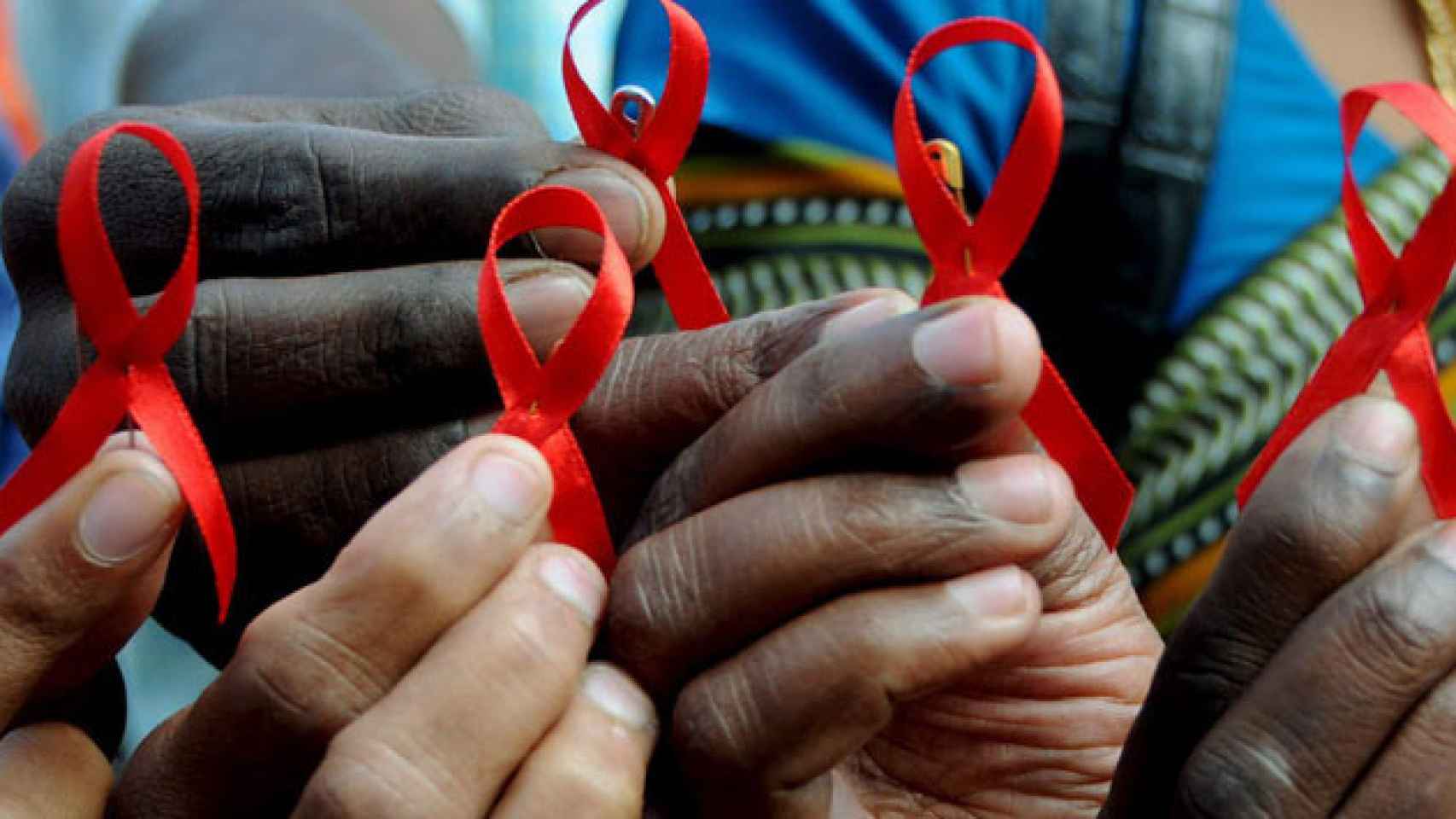 Varias personas sostienen un lazo rojo, símbolo de la lucha contra el VIH / CG