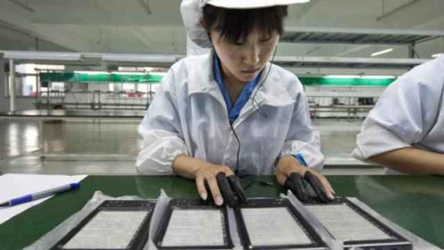 Una empleada en la cadena de montaje de dispositivos tecnológicos en una fábrica cerca de Pekín (China). Respuesta de las tecnológicas al coronavirus / EFE