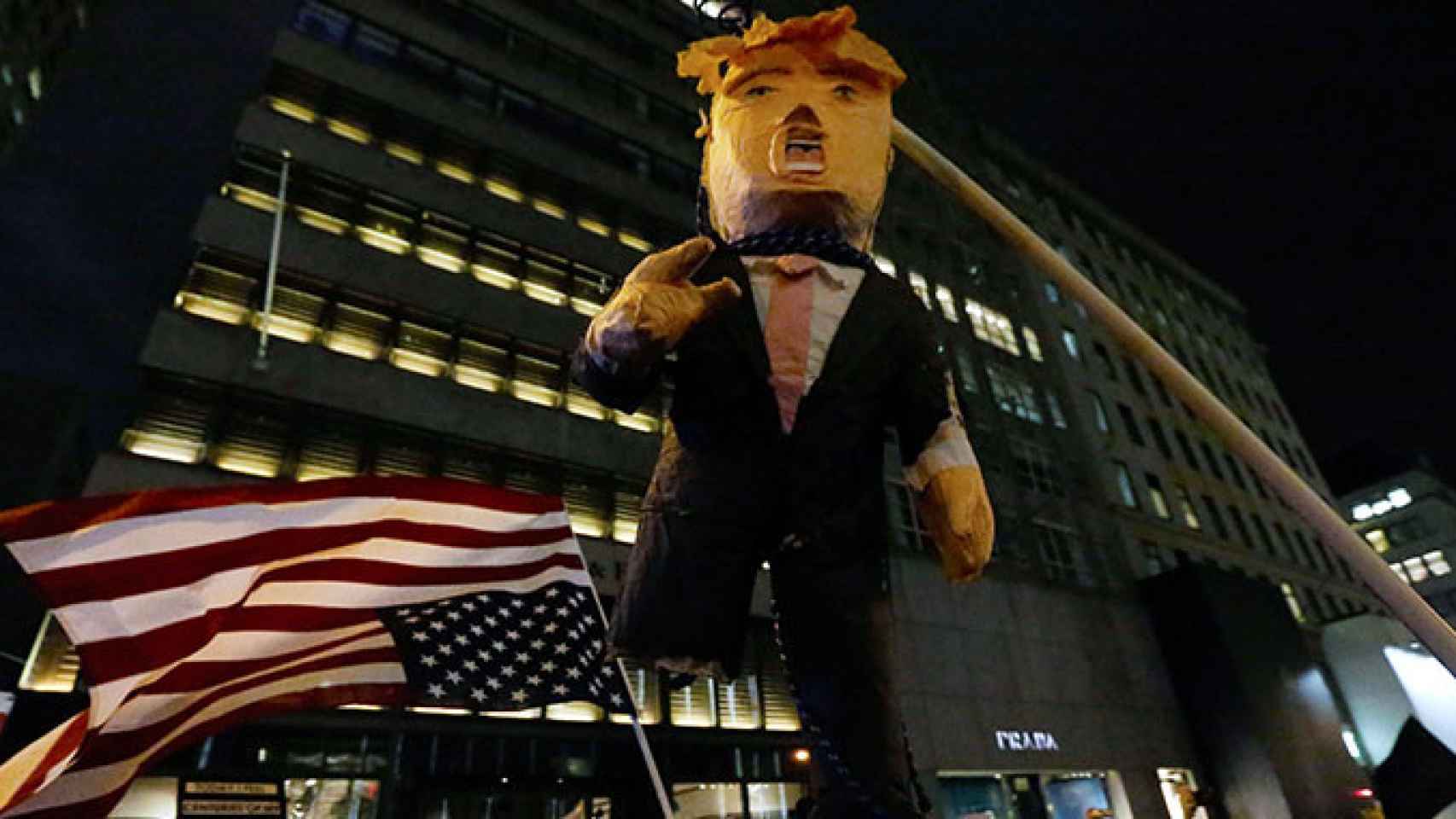 Una bandera de EEUU al revés y una figura que representa al próximo presidente del país, Donald Trump, en la manifestación de Manhattan / EFE