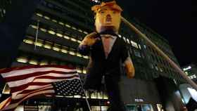 Una bandera de EEUU al revés y una figura que representa al próximo presidente del país, Donald Trump, en la manifestación de Manhattan / EFE