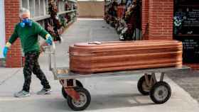 Imagen de un operario de servicios funerarios trasladando un ataúd en un cementerio de Valencia / EFE