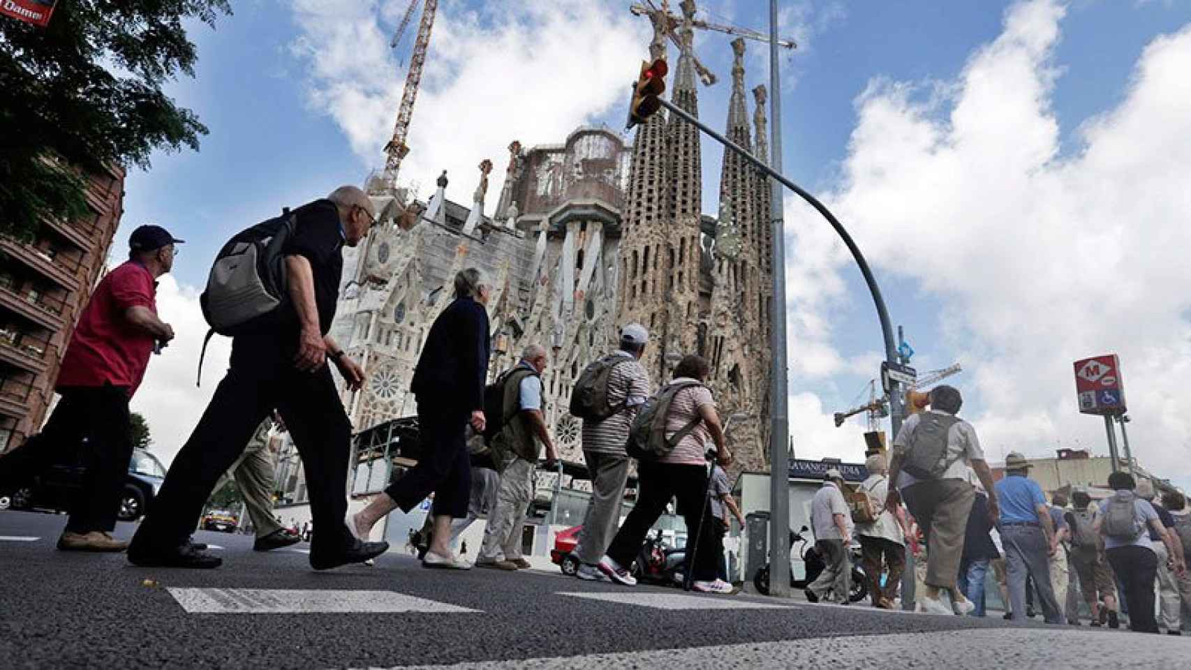 Un grupo de turistas cruza una calle en dirección a la Sagrada Família en Barcelona.