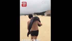 Una foto del turista cargando con el delfín