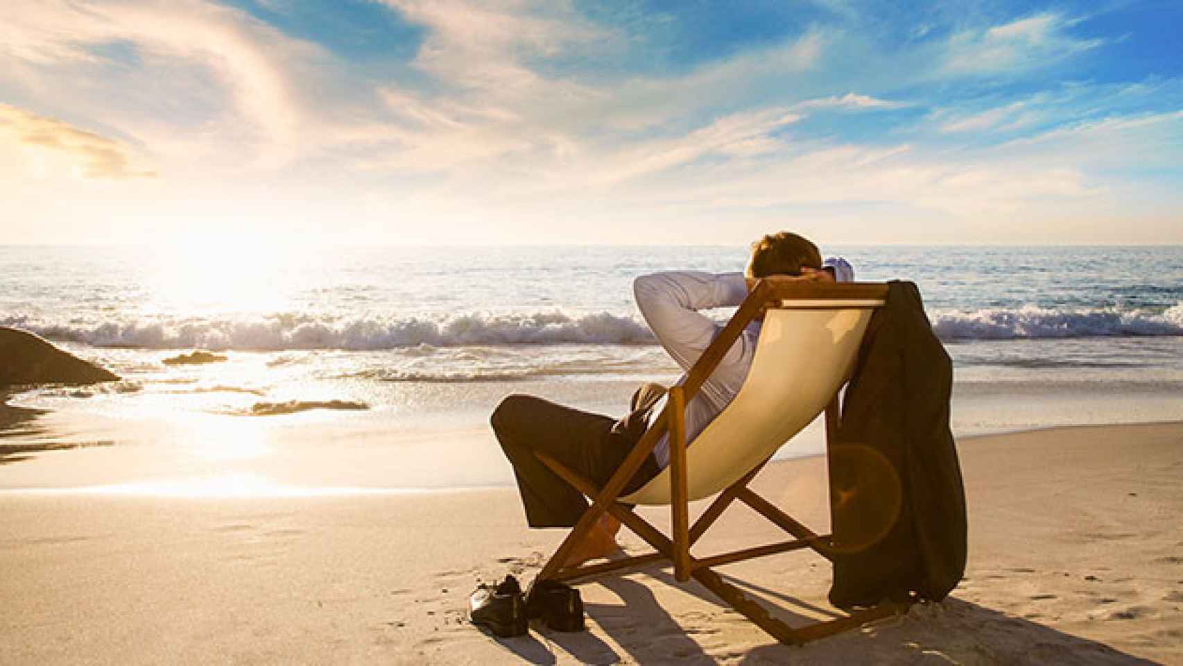 Un hombre se relaja en la playa vestido para ir al trabajo y puede sufrir síndrome posvacacional inverso / CG
