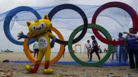 Vista de Vinicius, la mascota de los Juegos que posa junto a la escultura de los anillos olímpicos inaugurada por el ayuntamiento de Río de Janeiro hoy, en la playa de Copacabana.