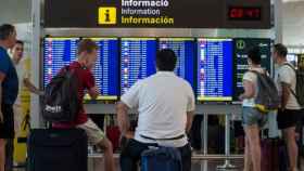 Imagen de dos pasajeros que observan la pantalla de horarios de los vuelos en el Aeropuerto de Barcelona-El Prat / EFE