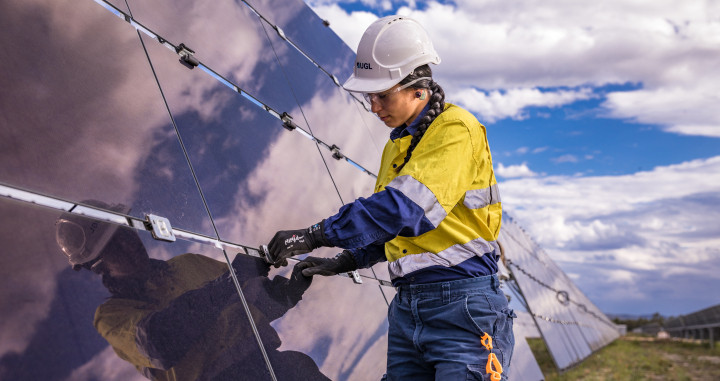 Una trabajadora instala una placa fotovoltaica en una granja solar / ACS