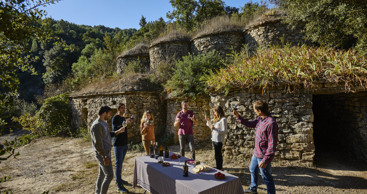 Un grupo de personas disfruta de una experiencia enoturística cerca de las construcciones de piedra seca / ACT