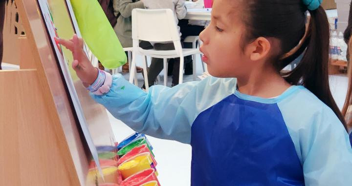 Una niña pintando en un taller de creatividad / CG