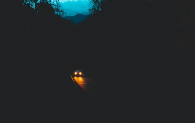 Luces de un coche mientras circula de noche / Joshua Woroniecki en UNSPLASH