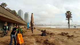 Un trabajador retira la arena de un restaurante de la playa del Somorrostro de Barcelona tras el temporal / EFE
