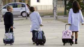 Tres niños con sus maletines escolares se dirigen al colegio. - EFE