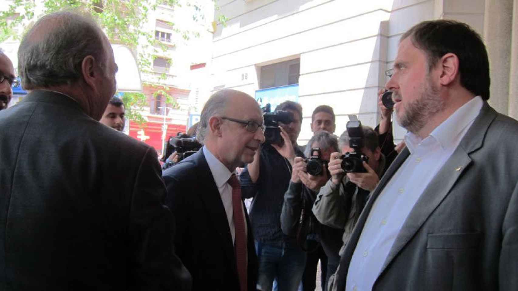 Cristóbal Motoro (centro), ministro de Hacienda, es recibido por el vicepresidente económico catalán, Oriol Junqueras, en la puerta de Foment del Treball.