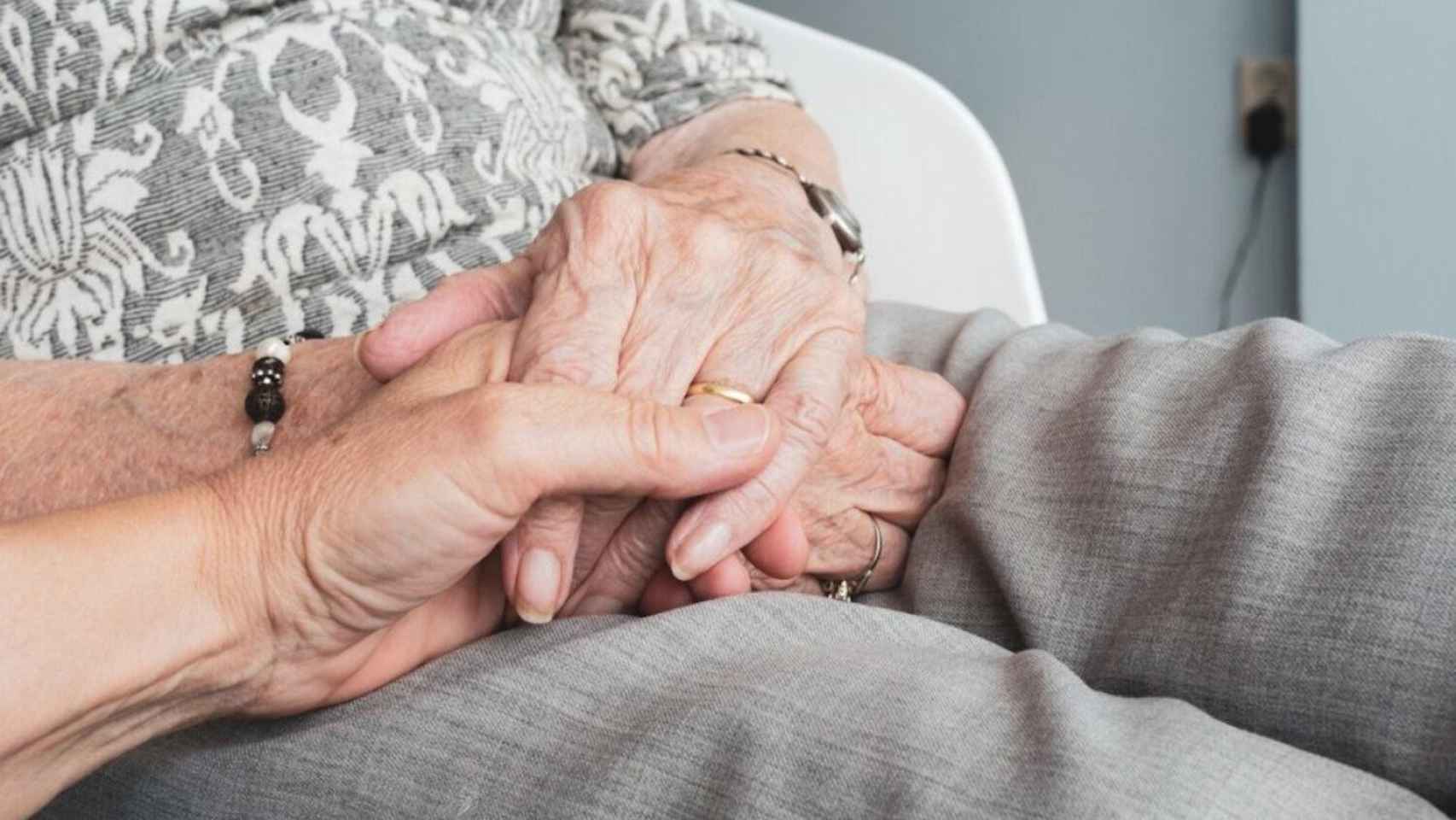 Dos personas mayores se dan la mano en un gesto de amor / EP
