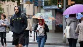 Unas personas pasean por Barcelona mientras llueve