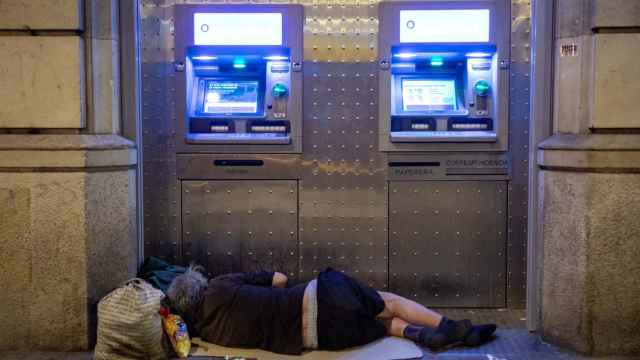 Una persona duerme bajo dos cajeros durante la realización del censo de personas en situación de sinhogarismo llevado a cabo por la fundación Arrels, a 15 de junio de 2022, en Barcelona