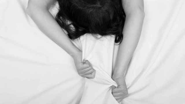 Una mujer agarra las sábanas con sus manos