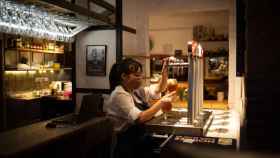 Una camarera sirve una cerveza en el interior de un bar en una calle céntrica de Barcelona