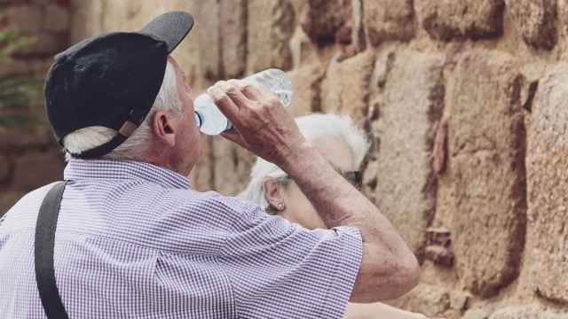 Un hombre mayor bebe agua de una botella en un día de intenso calor