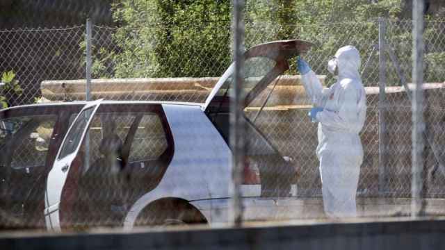 Un agente de la policía científica inspeccionando el coche en el que fue hallado el hombre asesinado en Roses