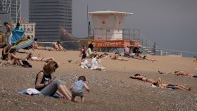 Varias personas toman el sol en la playa de la Barceloneta