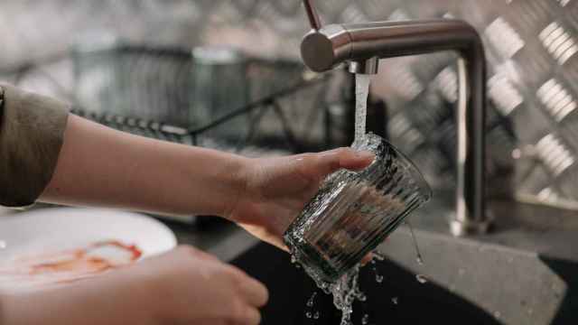 Una  persona lava un vaso con el agua del grifo