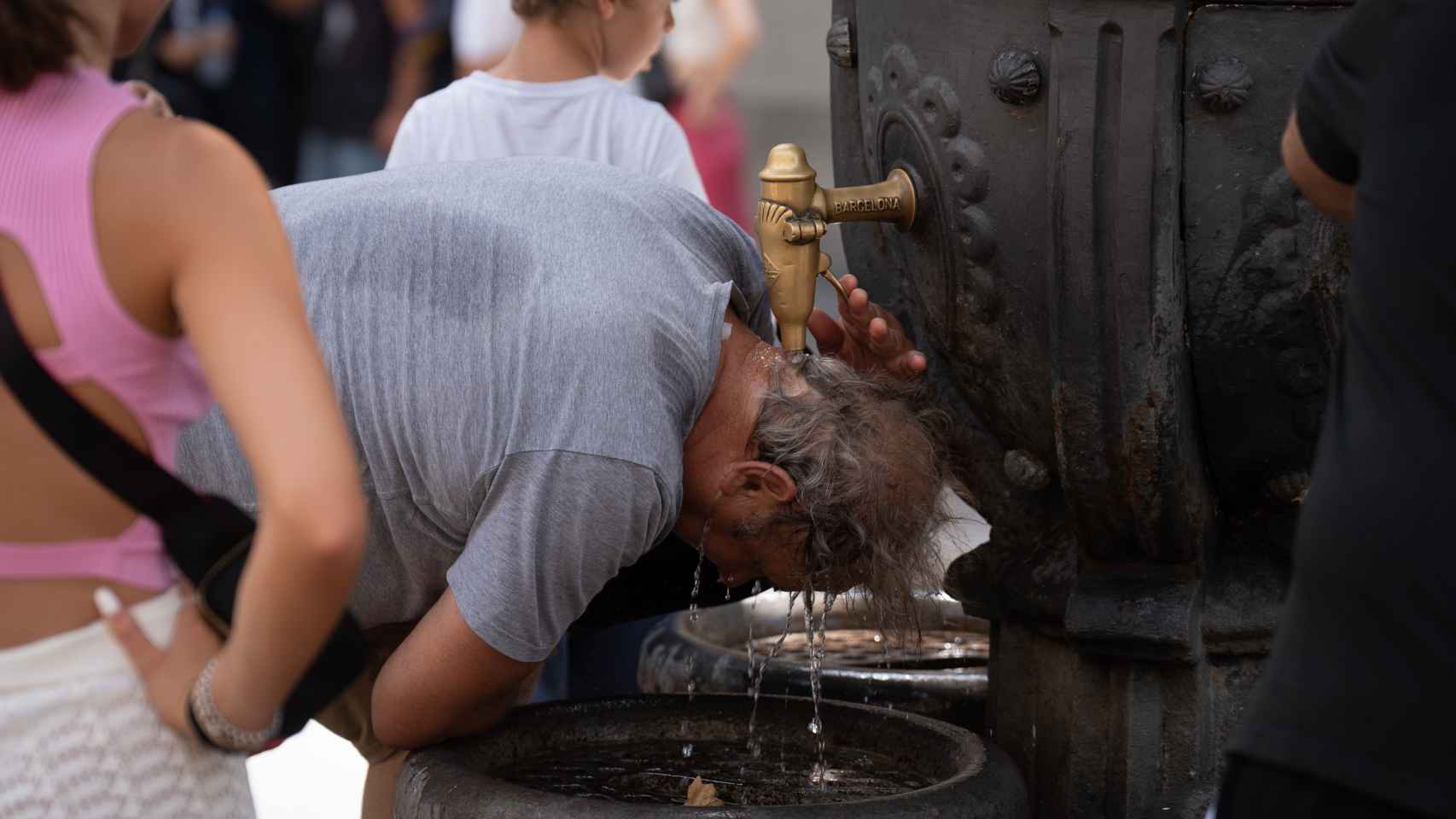 Una persona se refresca en la fuente de Canaletas, en Barcelona