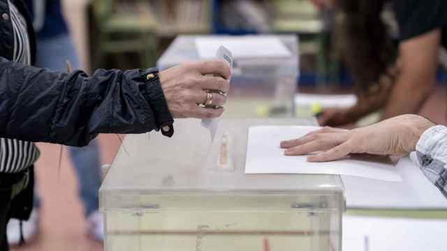 Una persona introduce su voto en la urna en un colegio electoral