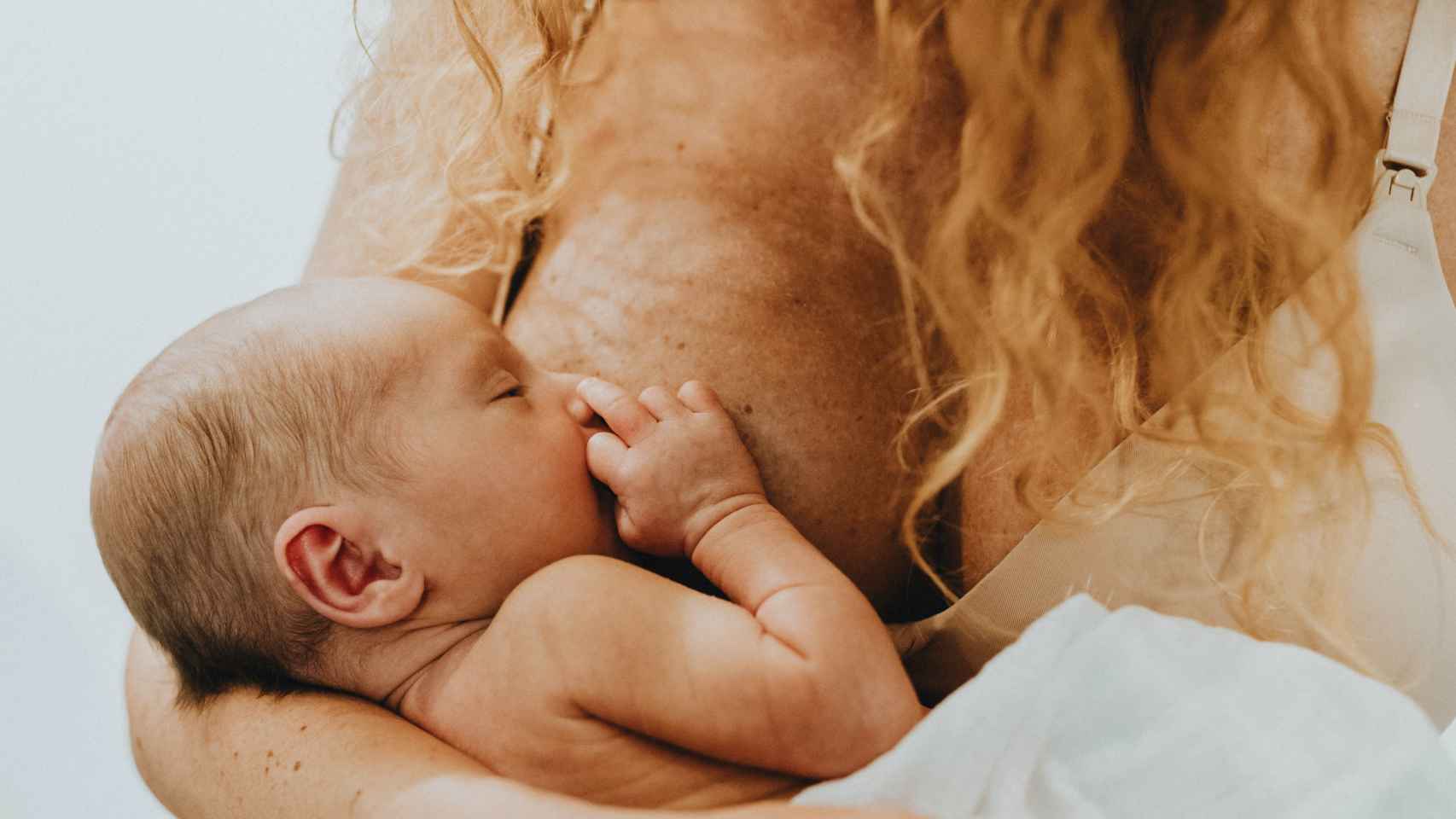Una mujer da de mamar a su bebé recién nacido