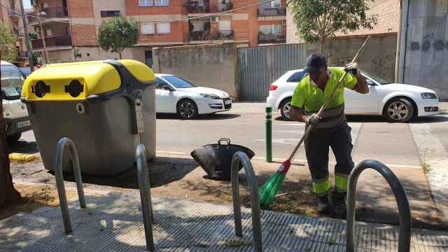 Un trabajador municipal limpia el lugar donde se ha quemado un contenedor en Lleida