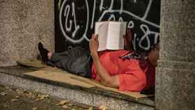 Una persona lee un libro en un portal durante la realización del censo de personas en situación de sinhogarismo llevado a cabo por la fundación Arrels, a 15 de junio de 2022, en Barcelona
