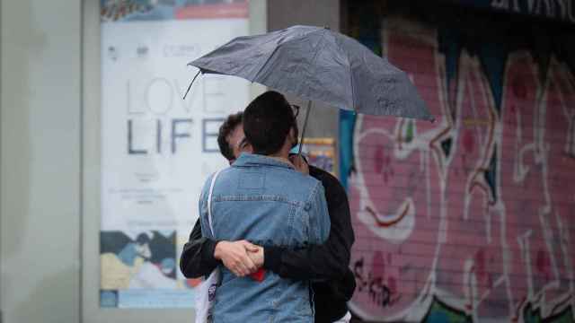 Dos chicos se abrazan bajo un paraguas, a 12 de mayo de 2023, en Barcelona, Cataluña