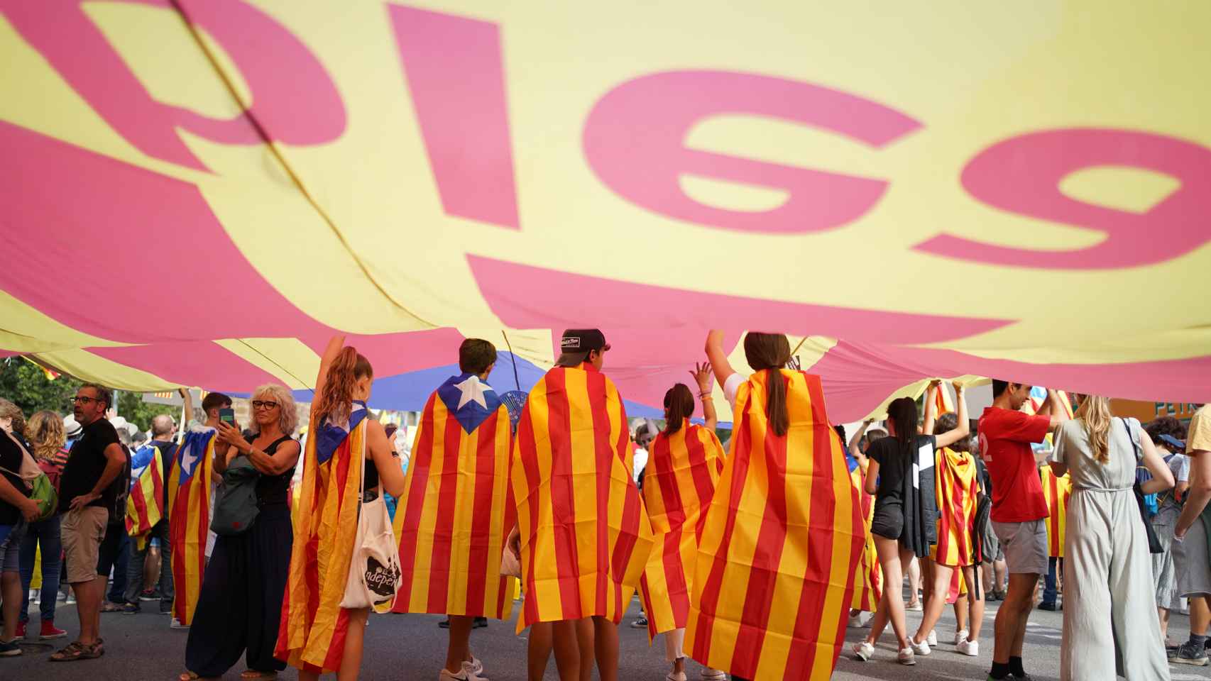 Varias personas visten con la bandera independentista de Cataluña en la manifestación convocada por la ANC con motivo de la Diada