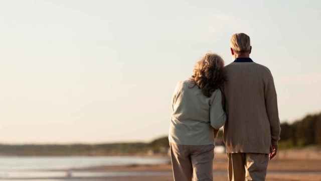 Una pareja de jubilados pasea por la playa