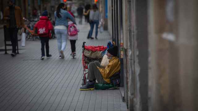 Una persona sin techo permanece en el suelo de una calle cercana al Hospital de campaña instalado en la parroquia de Santa Anna, en Barcelona, Cataluña, (España), a 14 de noviembre de 2020
