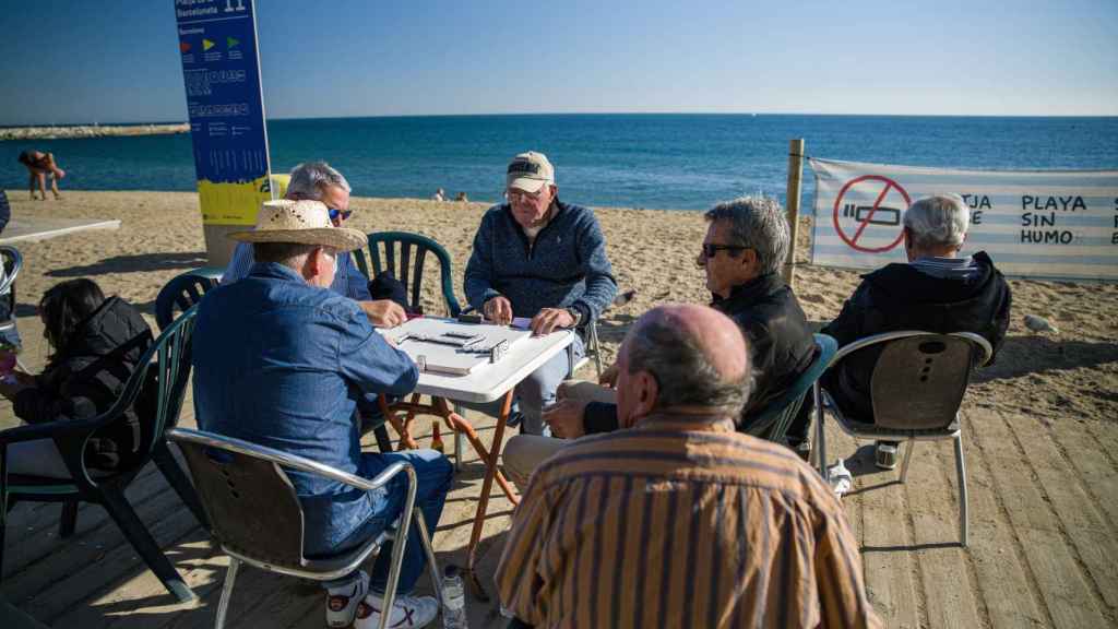 Unos hombres juegan al dominó en la playa de la Barceloneta