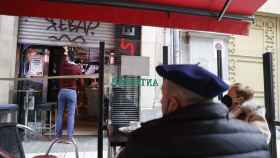 La propietaria de un establecimiento hostelero de Bilbao cierra la persiana ante la mirada de unos clientes. /EFE