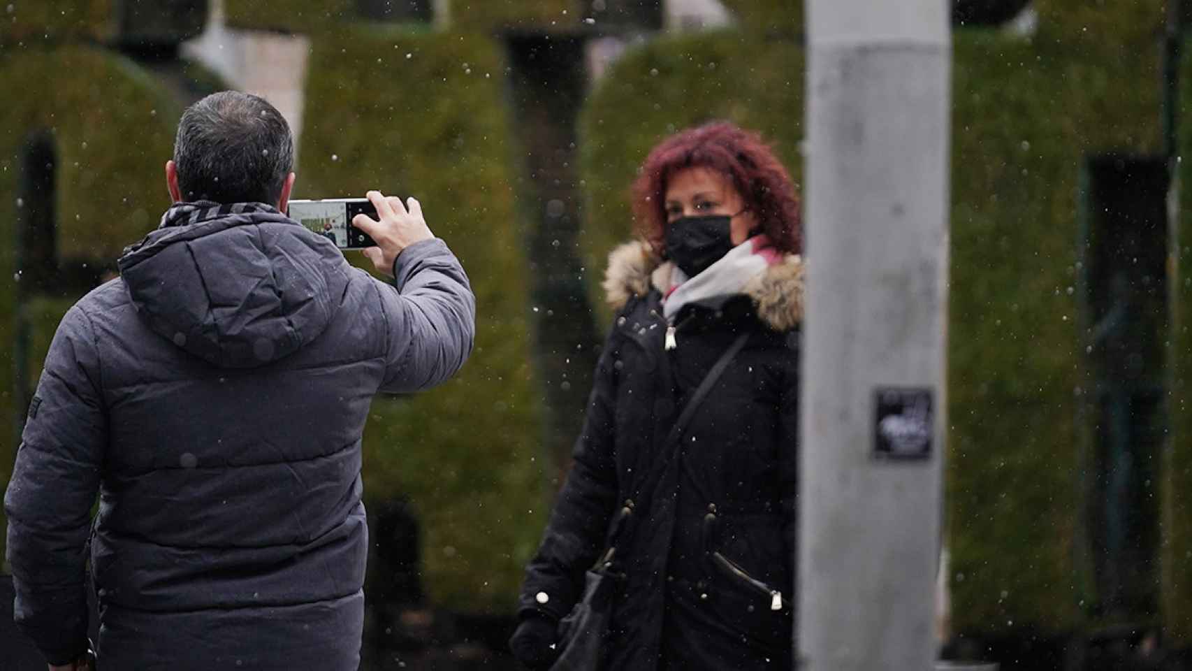 Un hombre fotografa a una mujer mientras caen copos de nieve en Vitoria / EUROPA PRESS