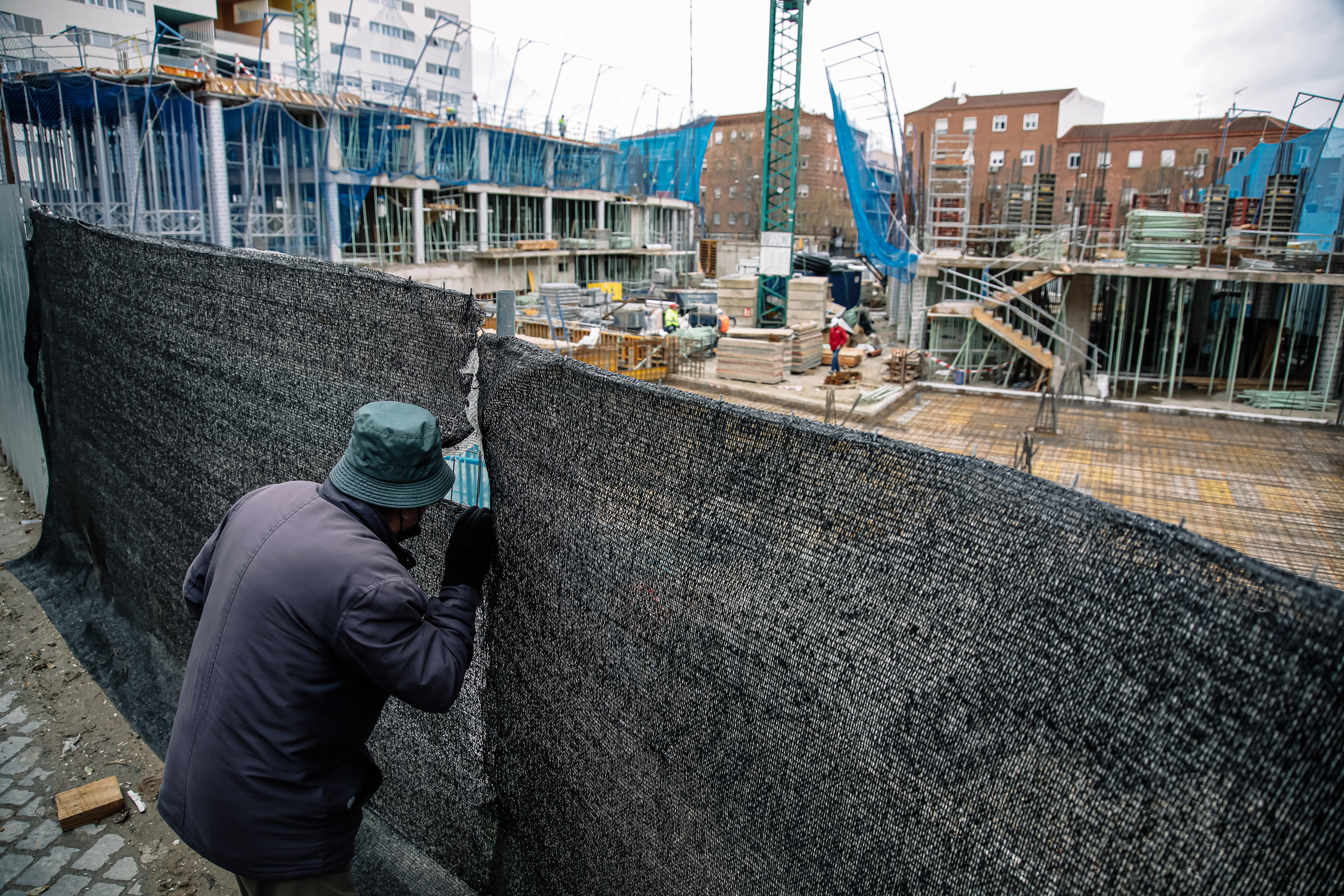 Un hombre mira por el agujero de una lona de una obra en construcción / Carlos Luján (Europa Press)